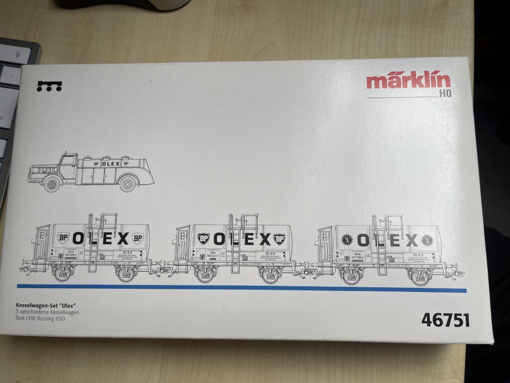Weiße Packung mit schwarz gezeichneten Kesselwagen mit der Aufschrift Olex und BP. Drei Kesselwagen mit Leitern und Bremserhäuschen und ein Tankwagen mit Aufschrift Olex.