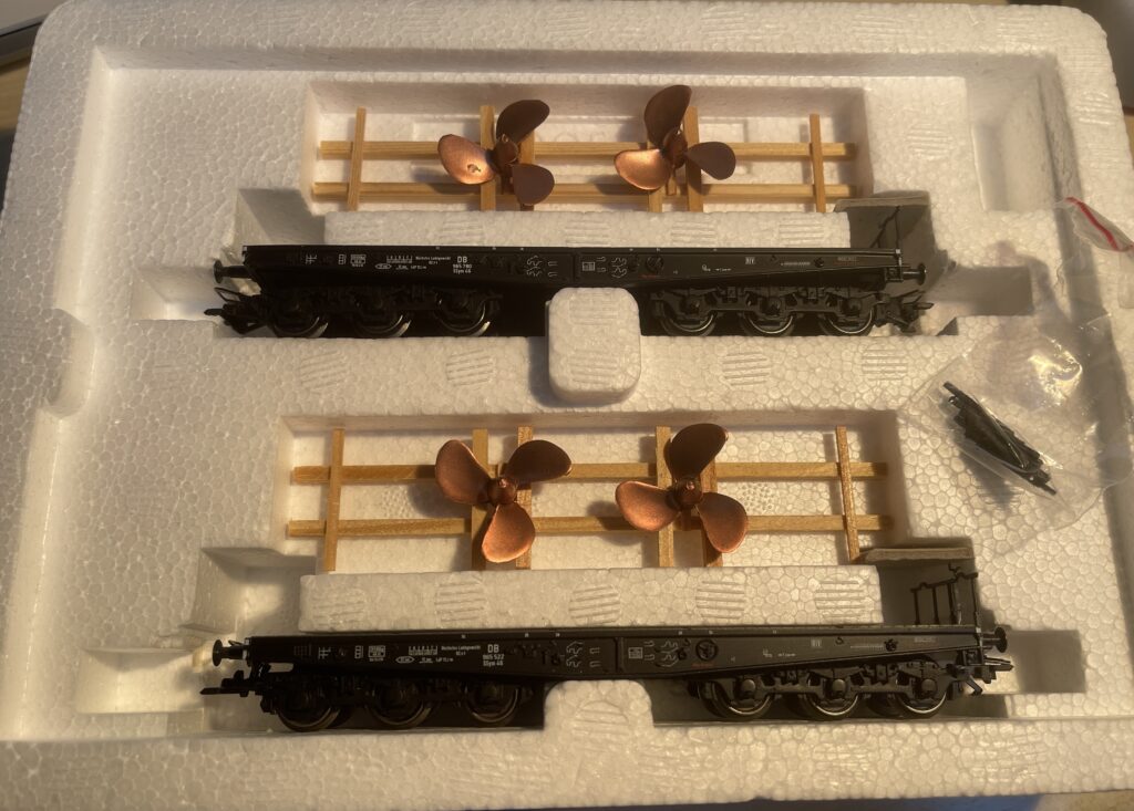 Die offene Packung in denen die zwei Flachwagen stecken. Jeweils darüber im Holzgestell zwei Schiffpropeller.