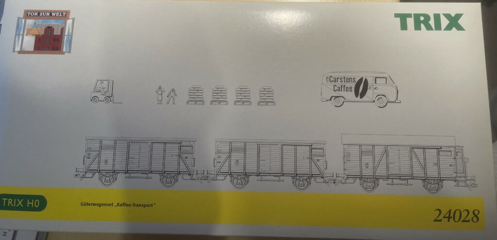 Die Packung mit dem gelben Rand unten und drei Güterwagen als Zeichnung. Darüber auch als Zeichnung ein Gabelstapler, zwei Menschen, Paletten mit Säcken und ein alter VW-Bus mit Carstens Caffee als Aufschrift.