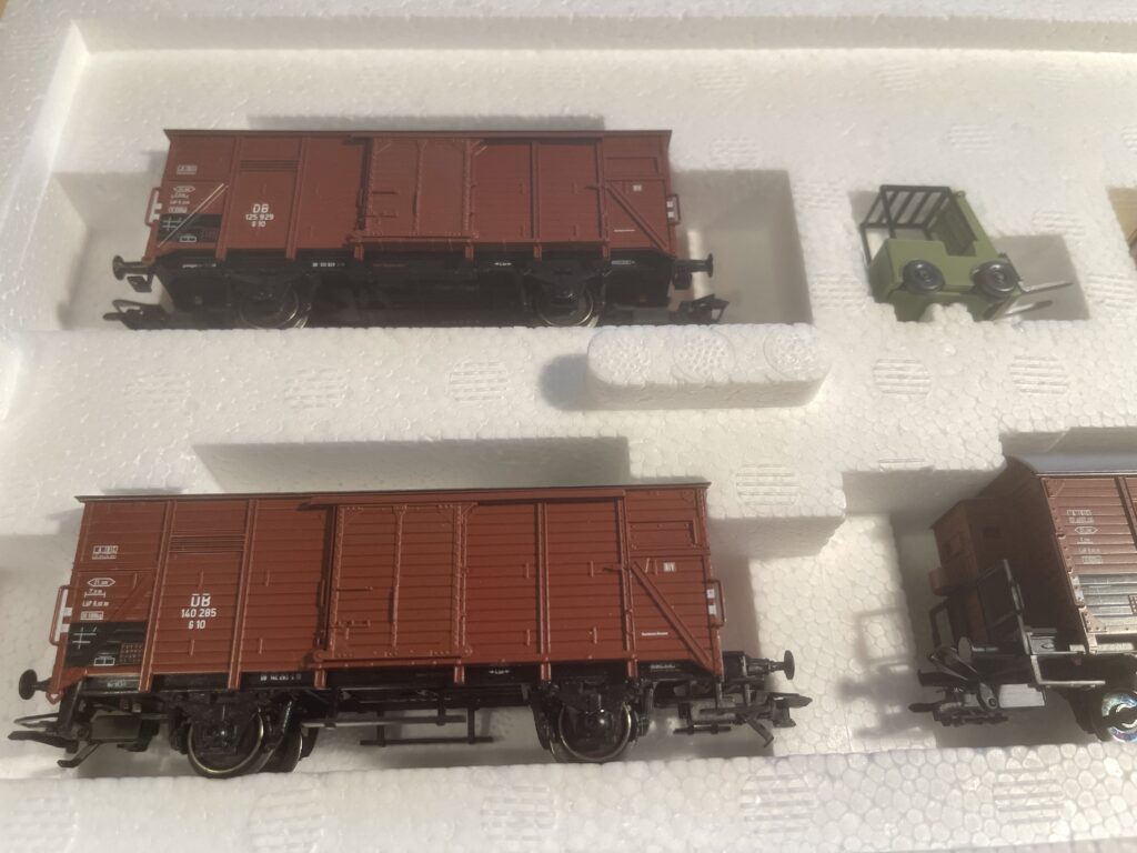 Zwei braune Güterwagen und ein grüner Gabelstapler in der Styropor Packung.