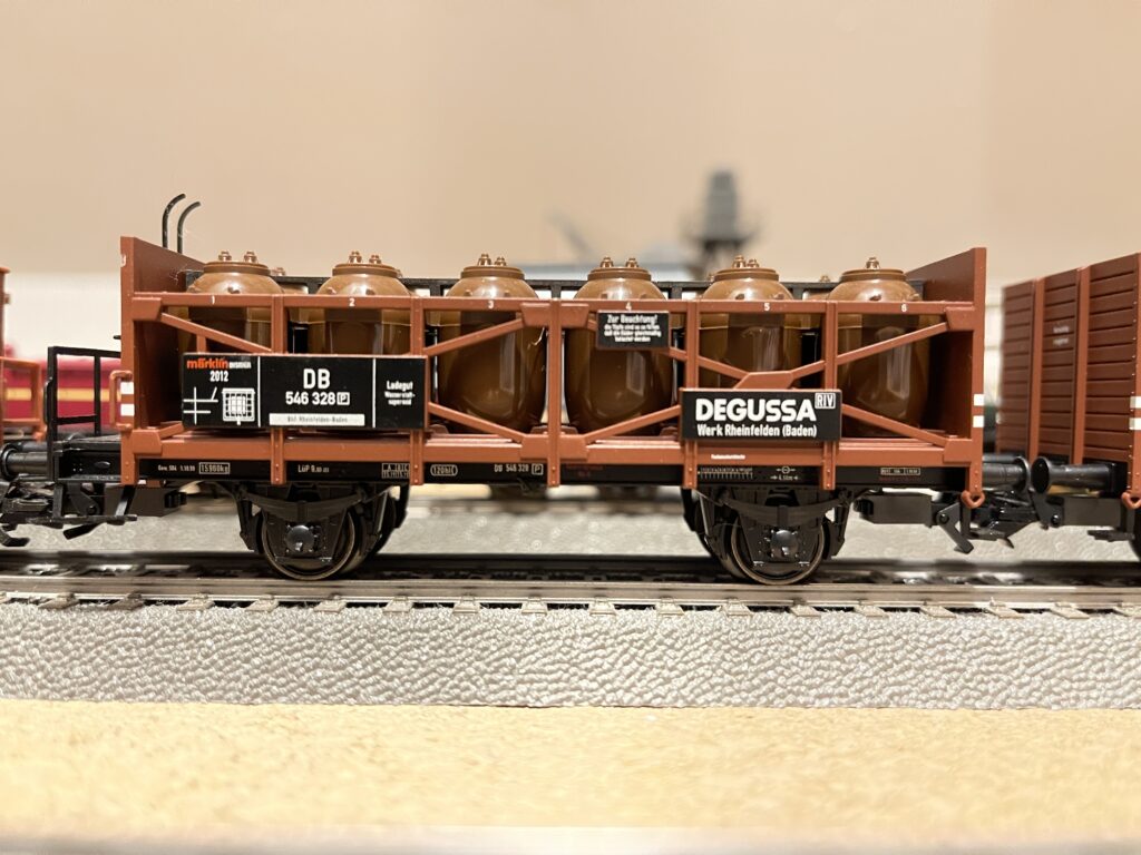 Brauner Säuretopfwagen mit Aufschrift DEGUSSA und DB auf einer grauen Schiene von Märklin.